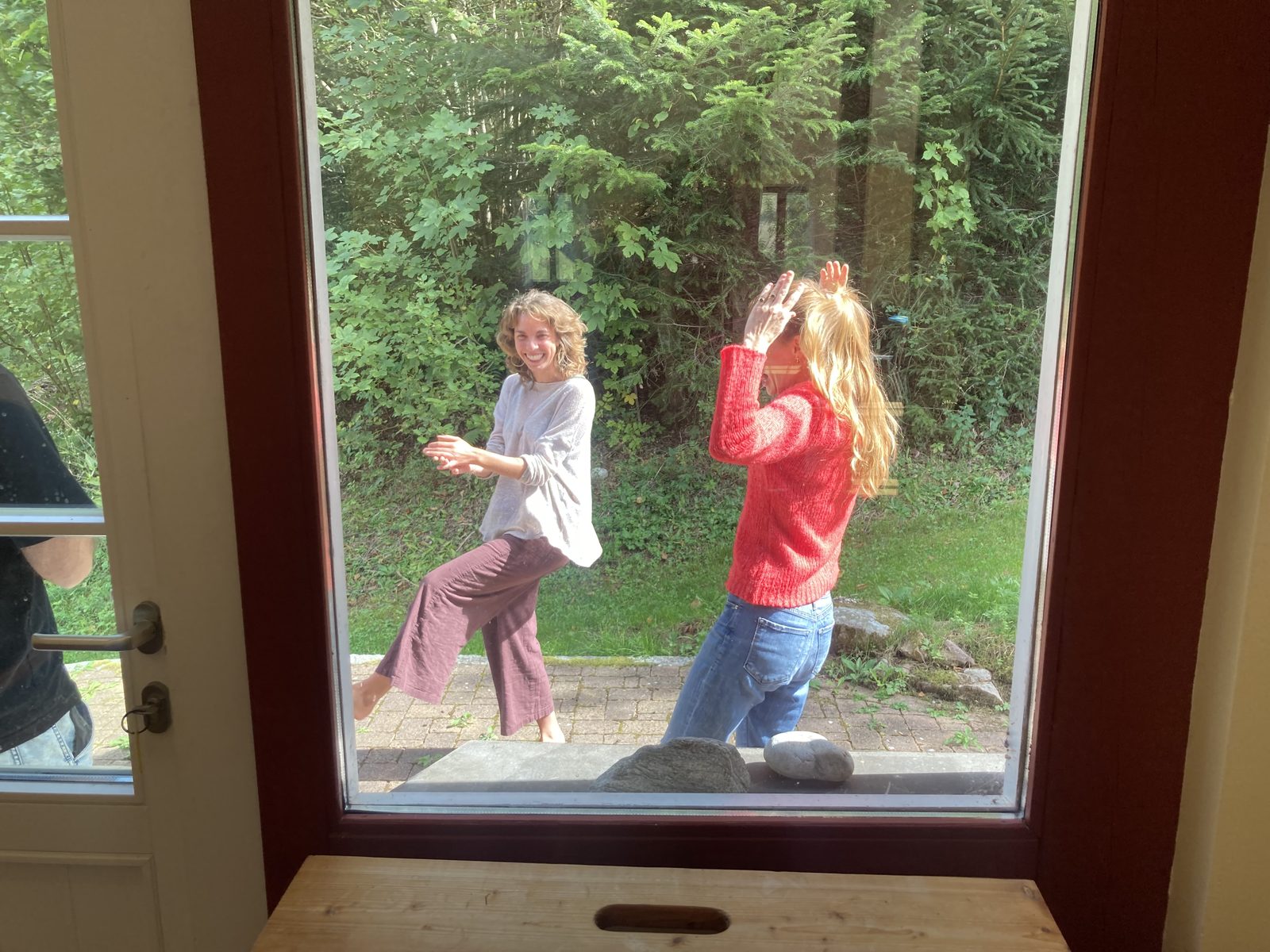 Two participants dancing in the garden, seen through the window