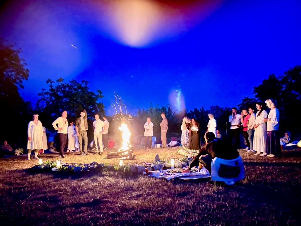 Students gathered in a circle around a fire at night during a seminar in Moldova