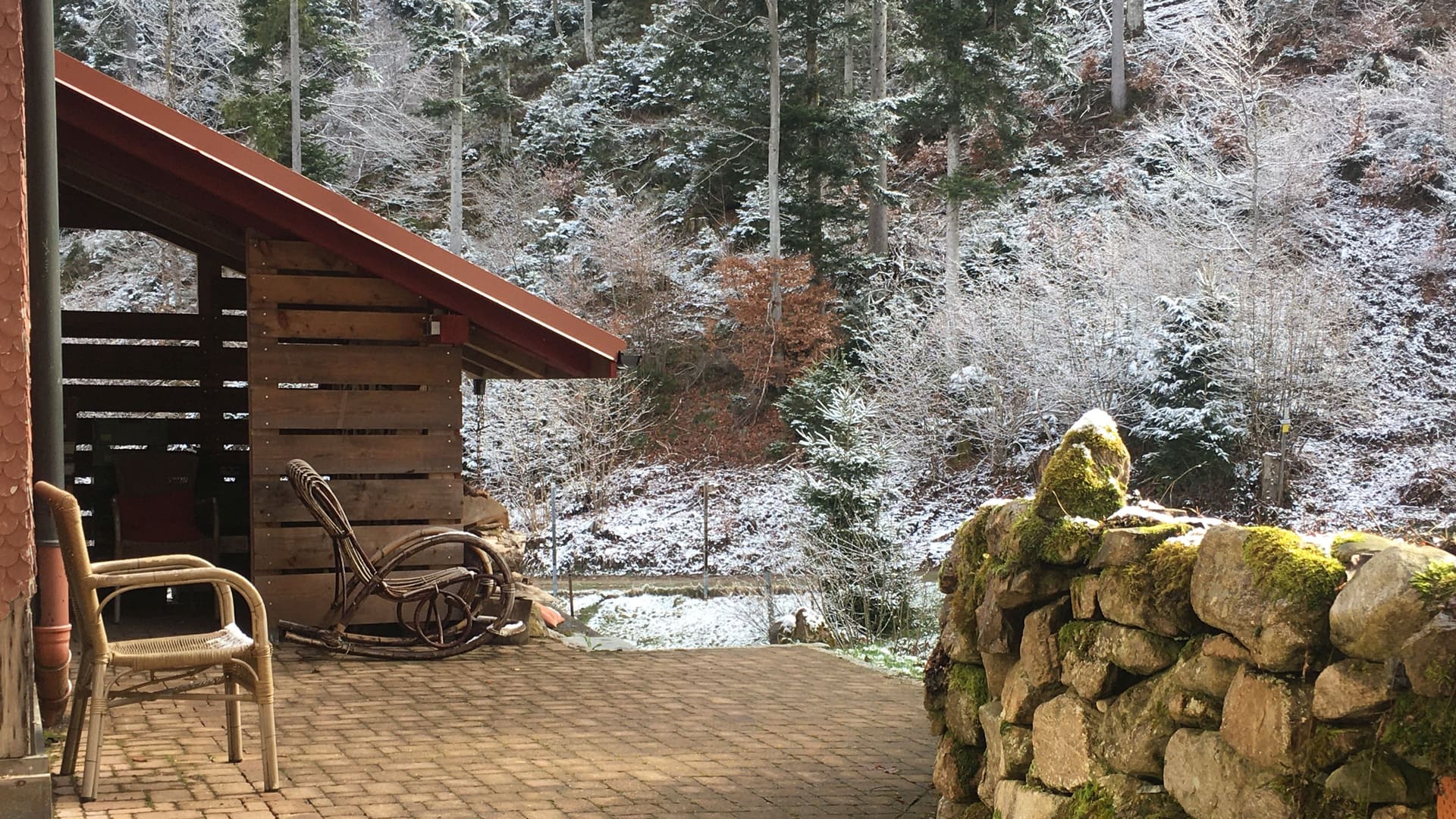 Wicker chairs on the snow-dusted terrace looking out to the winter Black Forest
