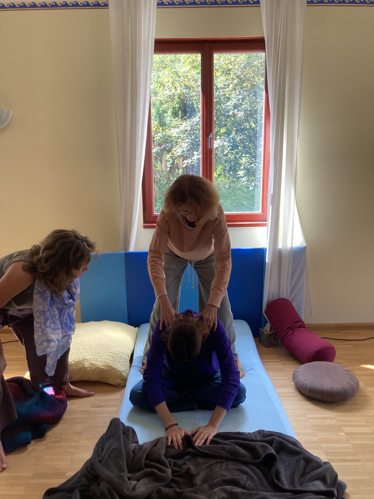 A facilitator supporting a kneeling participant's back