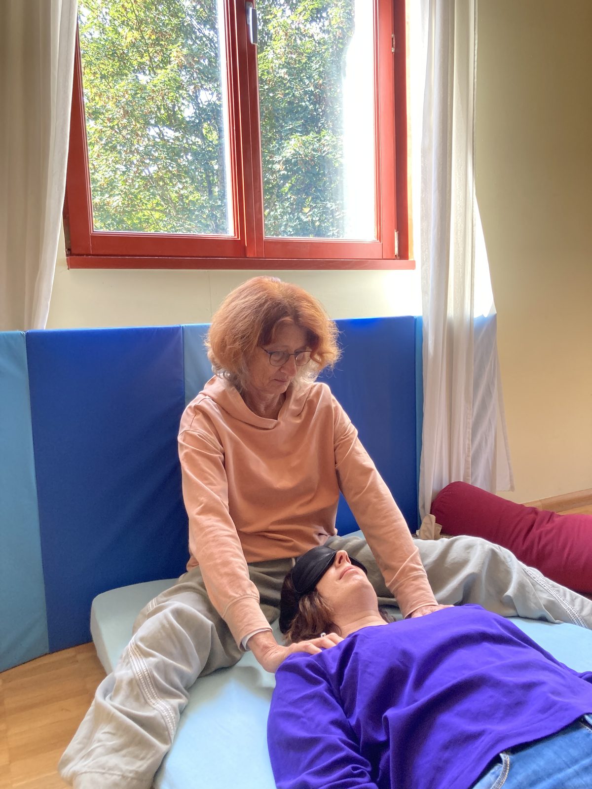 A facilitator working gently on the shoulders of a lying participant