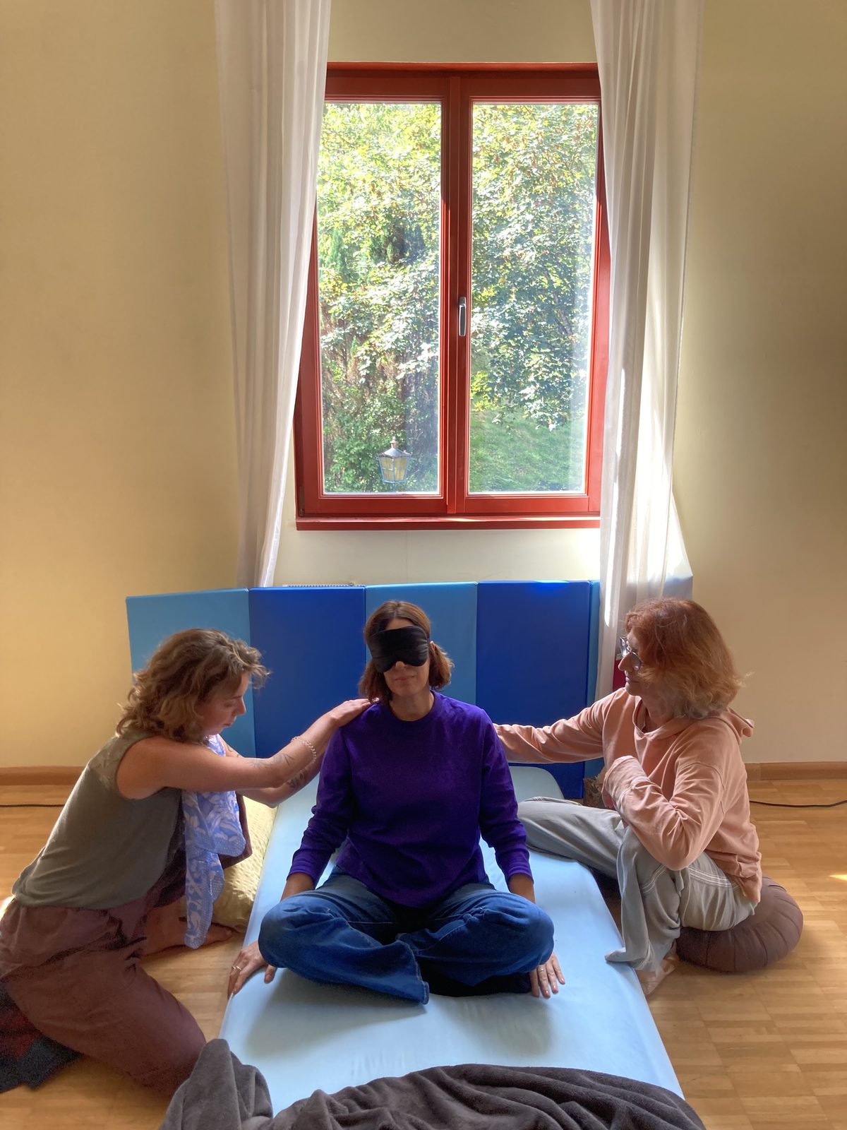 Two facilitators resting supportive hands on a seated participant's shoulders