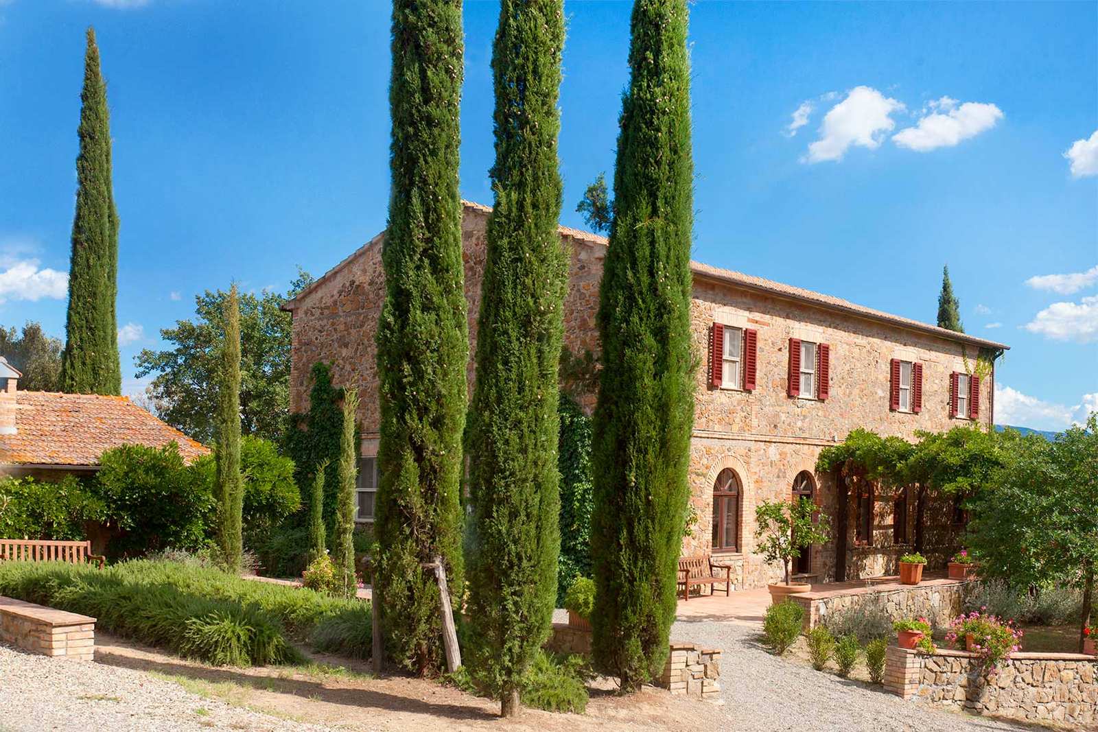 Stone farmhouse framed by tall cypress trees